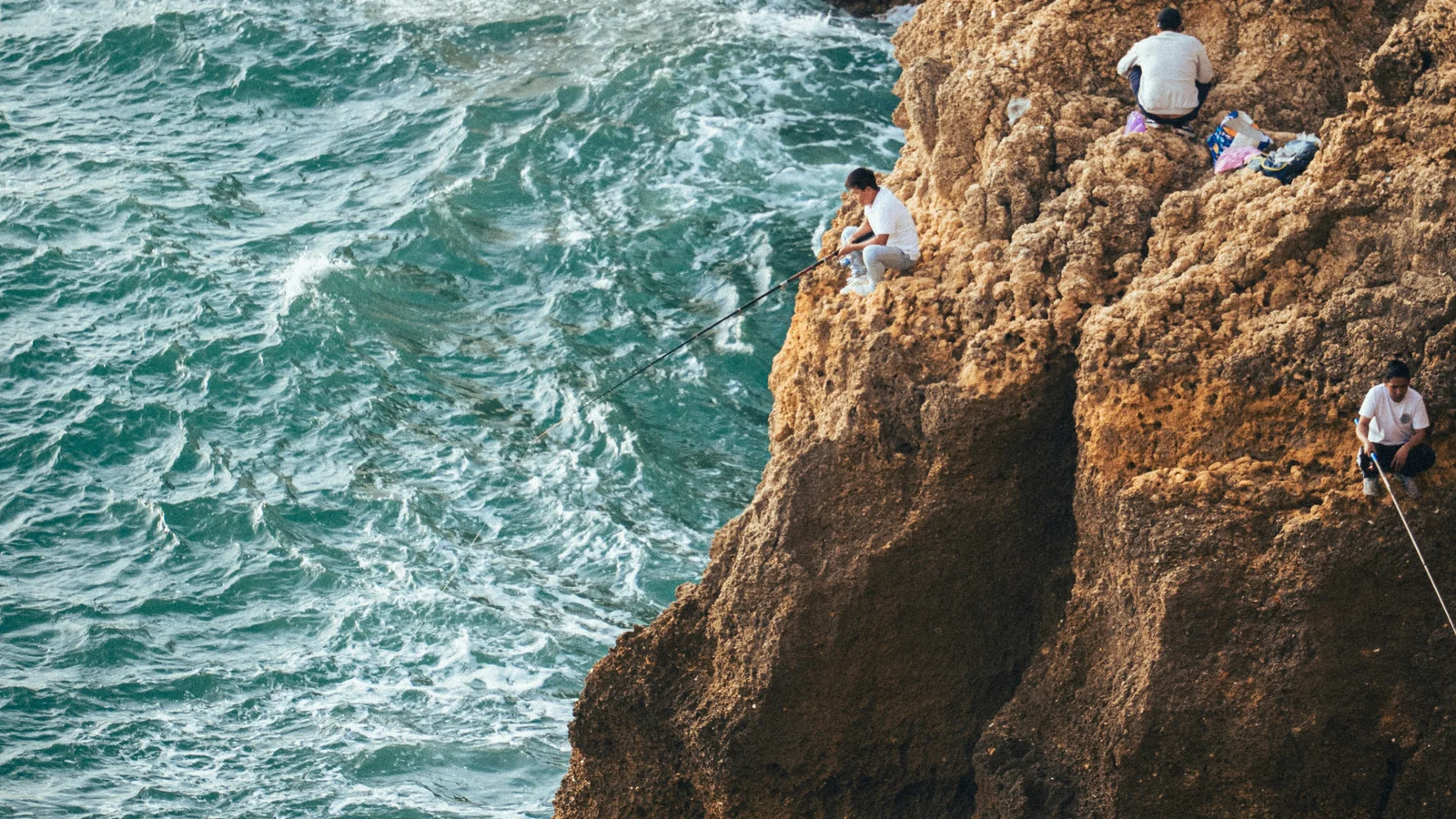 Anglers fishing from rugged cliffs above the Atlantic in Sagres, Portugal.